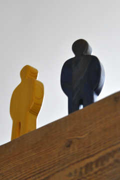 2 Holzfiguren stehen hoch auf einem Balken (Untersicht)