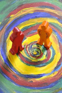 2 Holzfiguren stehen auf einer gemalten Spirale